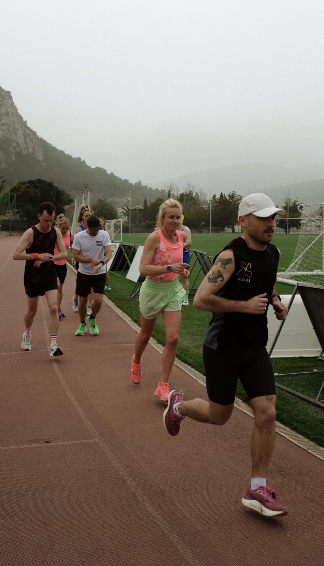 Group Interval Training at the Pollença Track A group of runners training together on the Pollença track, mid-interval, showing synchronized effort and determination.