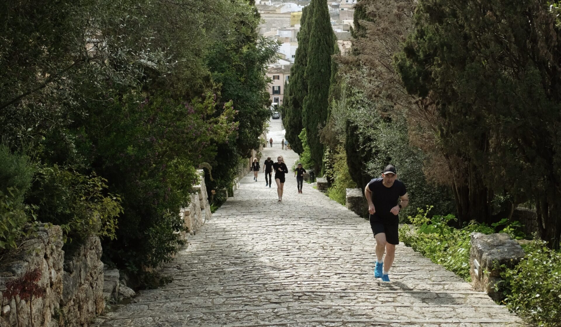 Running Group Climbing the Calvari Steps in Pollença A focused group of runners powering up the steep and historic Calvari steps in Pollença, Mallorca, during a training session.